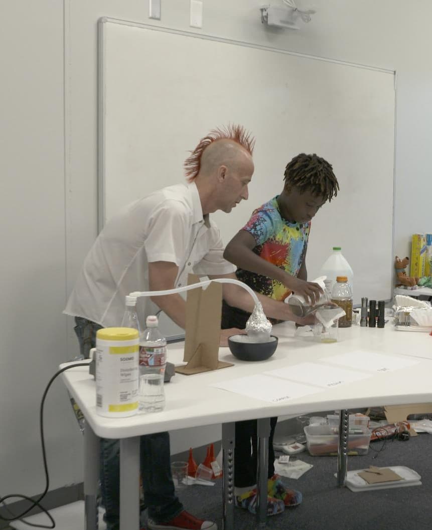 A student and teacher work on a science experience 
