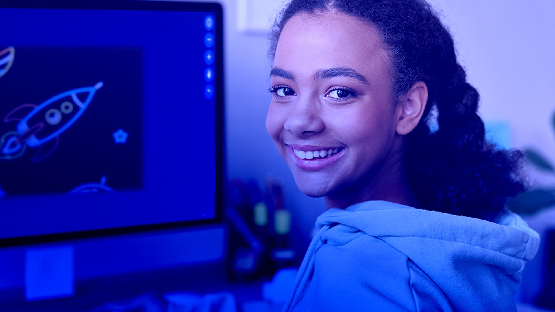 A smiling child shows off a digital postcard in progress on a computer